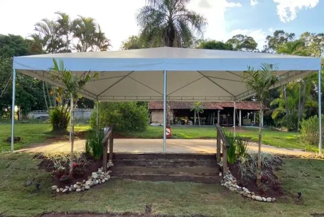 Tenda branca montada em jardim de chácara