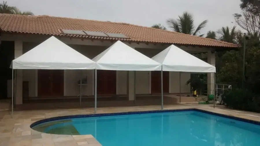 Três tendas piramidais unidas ao lado de piscina
